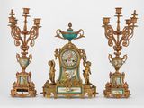 une horloge posée sur une table à côté de trois chandeliers