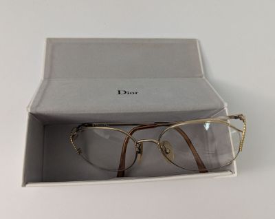 Des lunettes Christian Dior dans un étui posé sur une surface blanche