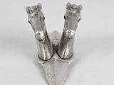 paire de figurines en métal argenté représentant des têtes de cheval, posées sur un support blanc