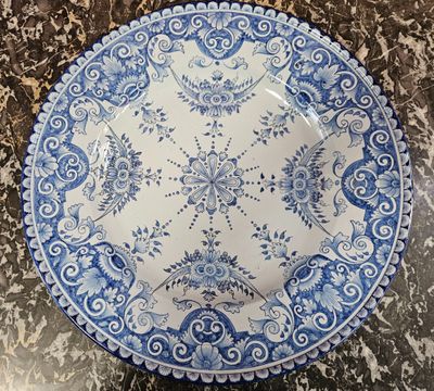 an old blue and white plate sitting on top of a marble counter