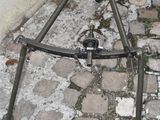 a metal tripod sitting on the ground next to a wall