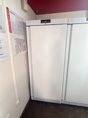 two white refrigerators in a room with a red wall