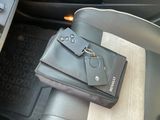 un sac à main noir muni d'un porte-clés, posé sur le siège d'une voiture
