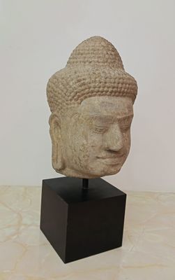 sculpture of a head of a buddha on a wooden stand