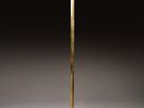 a tall brass floor lamp with a white shade on top of it