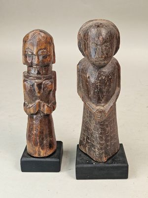 two wooden figurines of a man and a woman on black bases