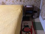 a bed with a yellow bedspread and a rug on the floor