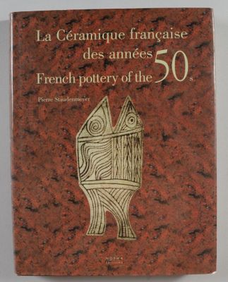 Le livre est posé sur une table près d'un mur blanc.
