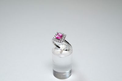 an image of a pink diamond ring sitting on top of a clear glass