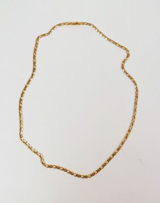 gros plan d'un collier à chaîne en or sur une surface blanche