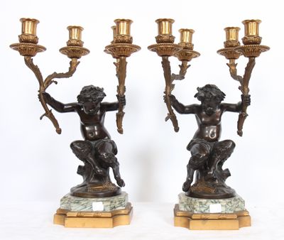 pair of bronze figurines of a boy and a girl holding a candelabra