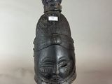 une sculpture noire représentant une tête surmontée d'une couronne