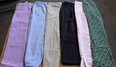 cinq paires de pantalons posées sur une table à côté d'une cravate