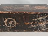 une vieille boîte en bois ornée d'un motif représentant un bateau et une boussole