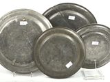 four silver plates with labels on them sitting on a white surface