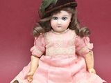a doll that is sitting on the ground with a hat on