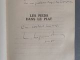 un livre ouvert, dont une page est recouverte d'une écriture manuscrite, posé sur une table