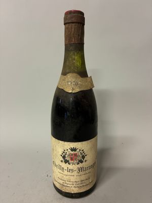 an old bottle of wine sitting on top of a white table