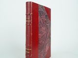 un vieux livre rouge posé sur une surface blanche