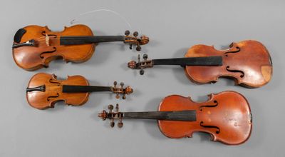 four antique violin ' s on a gray surface