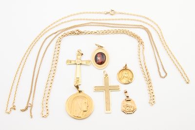 plusieurs colliers et pendentifs en or posés sur une surface blanche