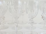 several empty wine glasses lined up in a row on a white surface