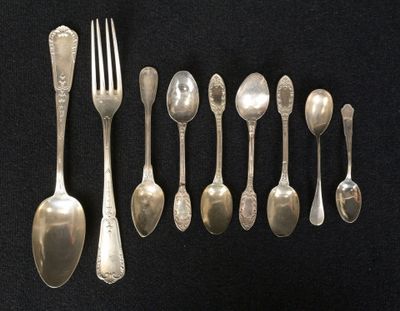 a lot of silver spoons and forks on a black table