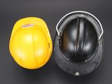 yellow hard hat next to a black hard hat on a black background