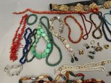 many different necklaces and bracelets laid out on a table