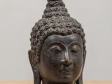 a close up of a statue of a buddha head on a table