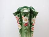 a green vase with pink and white flowers on it