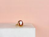 un gros plan d'une bague en or ornée d'un coquillage, posée sur un bloc de marbre
