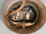 an old helmet with a leather strap on it sitting on top of a table