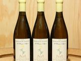 trois bouteilles de vin posées sur un tonneau en bois