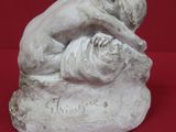 statue d'un homme allongé sur un rocher, sur fond rouge