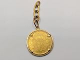 a close up of a gold coin on a chain on a white surface
