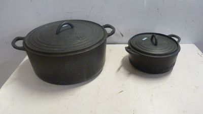 deux casseroles noires posées sur une table, sur fond blanc