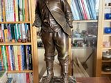 a bronze statue of a boy standing on a table