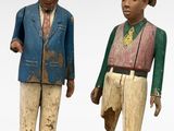 pair of wooden figurines of two men with hats and jackets