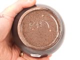a person holding a jar of chocolate colored eyeshadow
