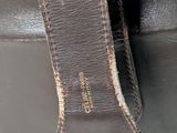 the back of a brown leather bag with a brown strap
