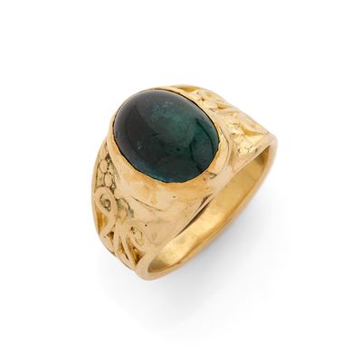 gros plan d'une bague en or avec une pierre verte