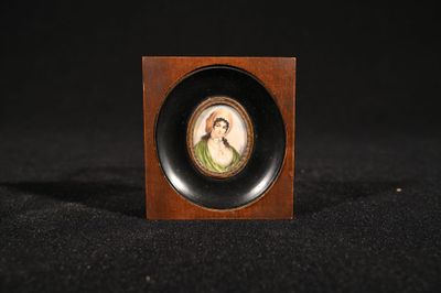 a miniature picture of a woman in a green dress in a wooden frame