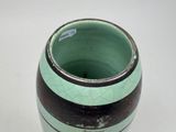 a green and black vase sitting on a white table