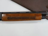 a shotgun that is laying on top of a leather case