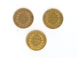 three different types of gold coins on a white surface