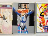 Trois livres sur les anime sont alignés sur une surface blanche