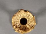 an image of a gold vase with a black center on a white surface