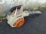 an orange and black blower sitting on the ground next to a concrete wall