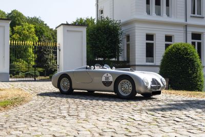 a silver sports car parked in front of a white house